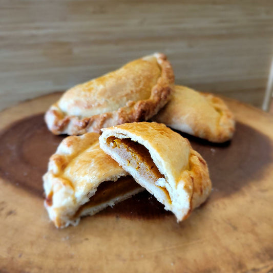 Pumpkin empanadas on a wooden tray.