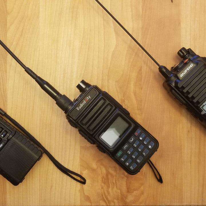 Three GMRS handheld radios against a wood background