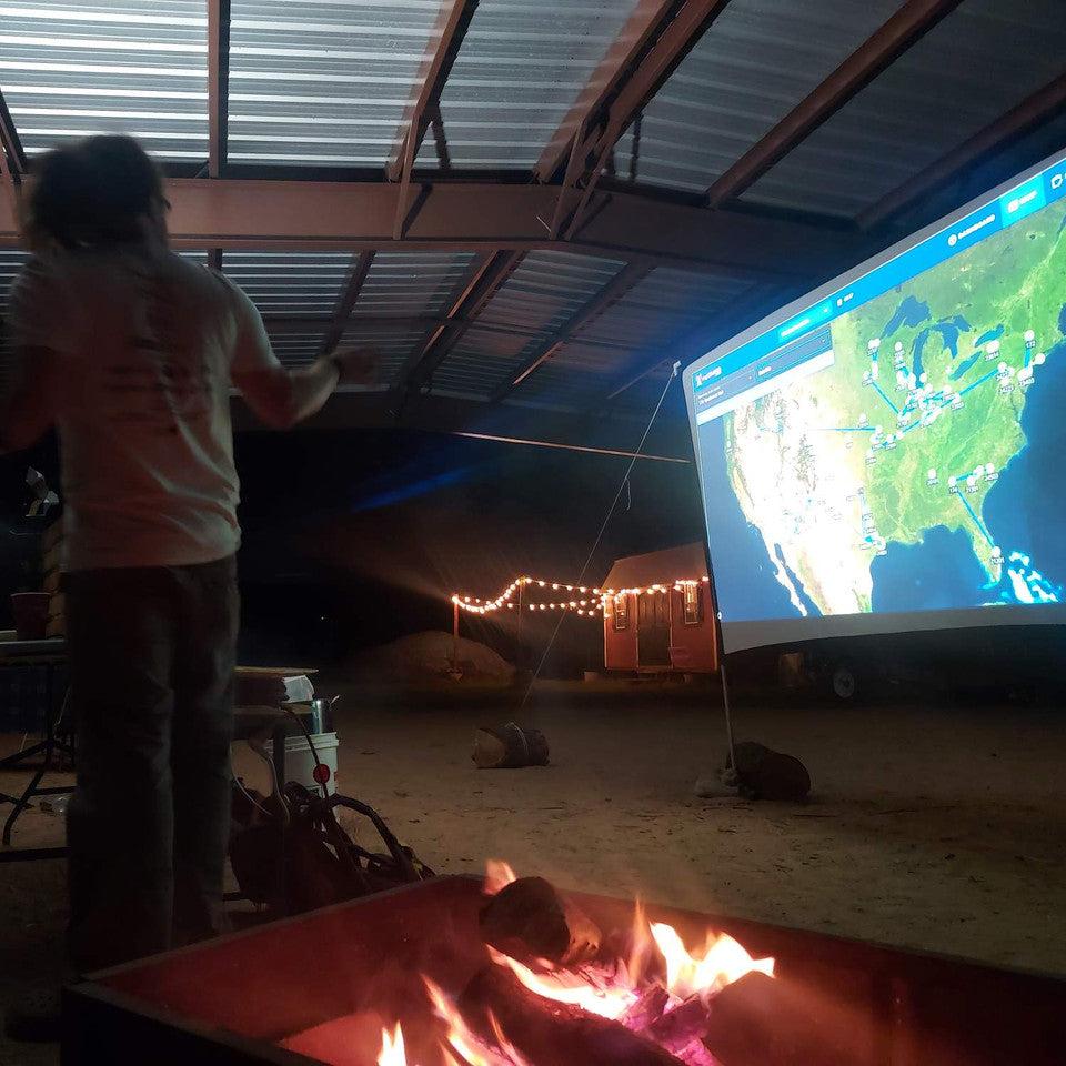 A campfire in the foreground with a projected image of nationwide GMRS radio repeater networks in the background