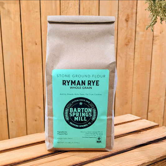 A bag of Ryman Rye whole grain stone ground flour from Barton Springs Mill on a wooden crate.